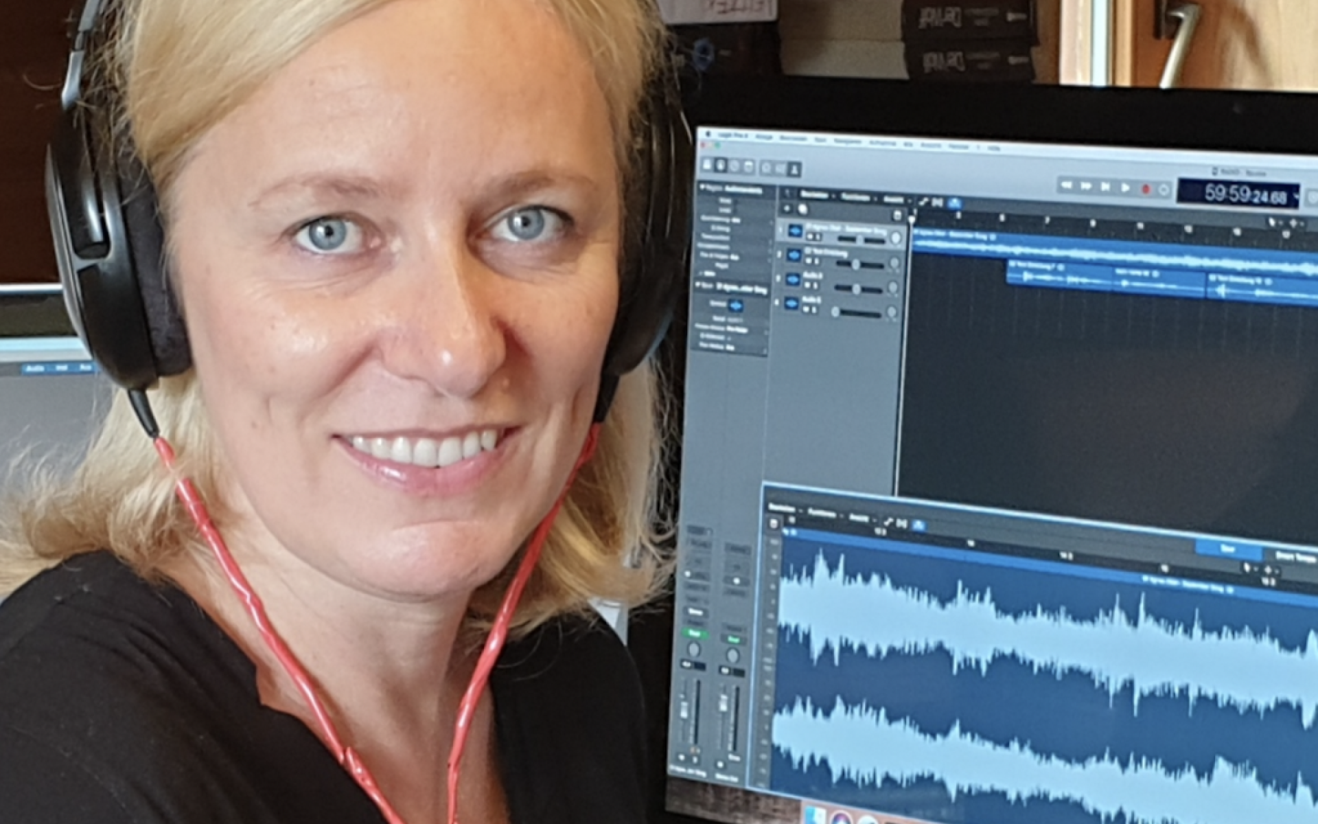 Frau mit Kopfhörern vor Computerbildschirm