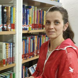 Roswitha Köberl neben einem Büchereiregal
