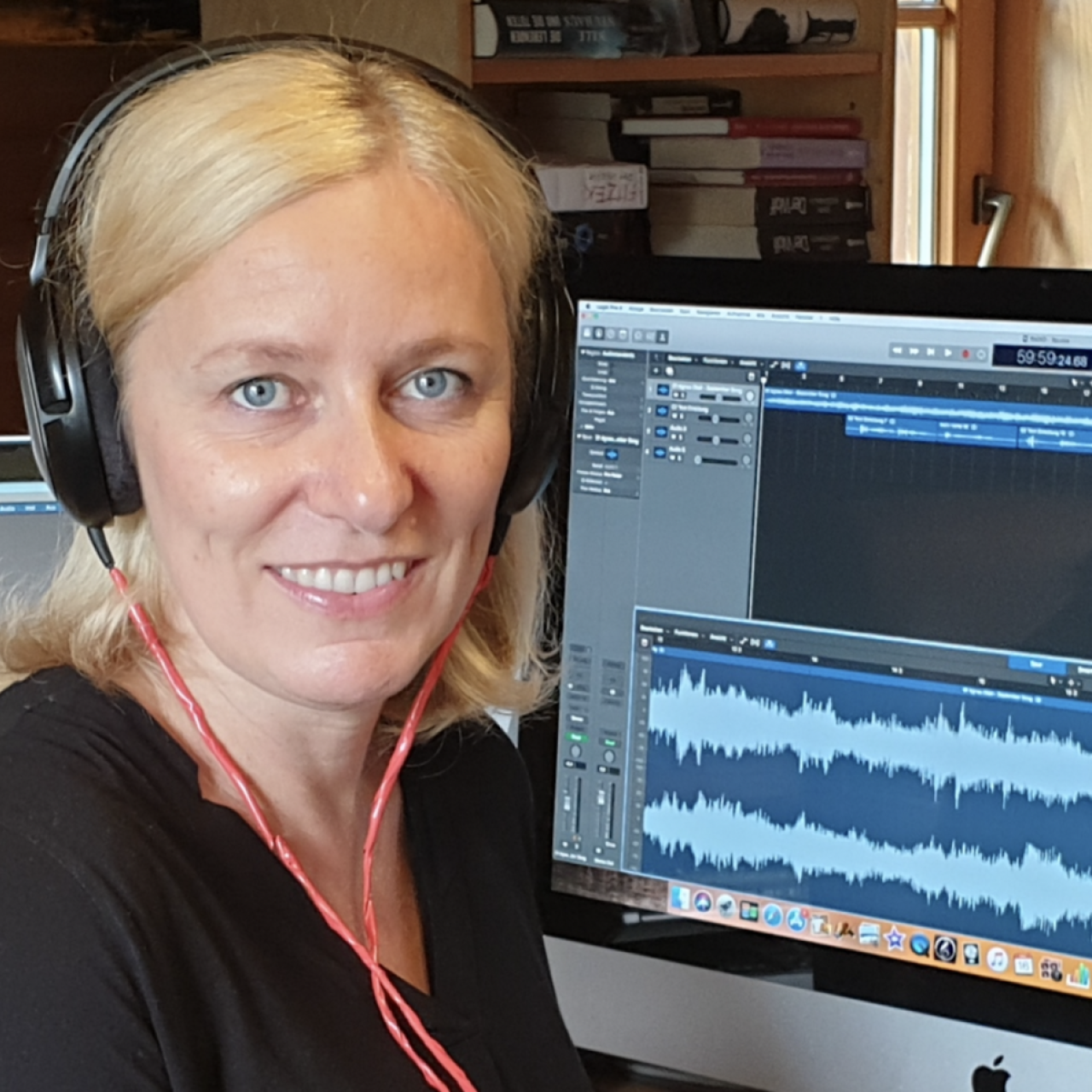 Frau mit Kopfhörern vor Computerbildschirm